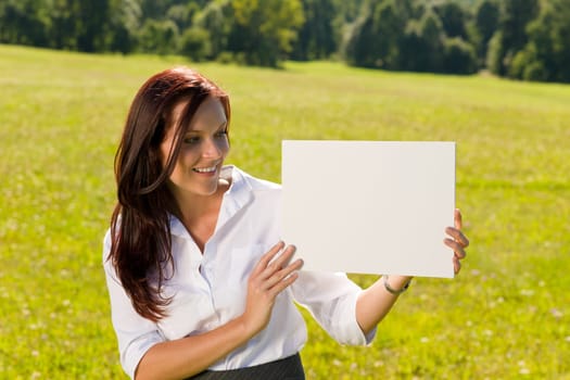 Young businesswoman sunny meadow looking aside at blank advertising banner