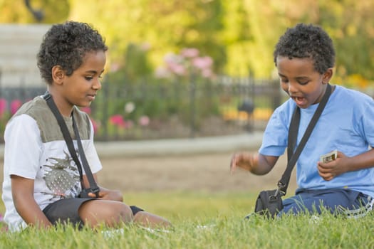 Two young kids playing cards in the park