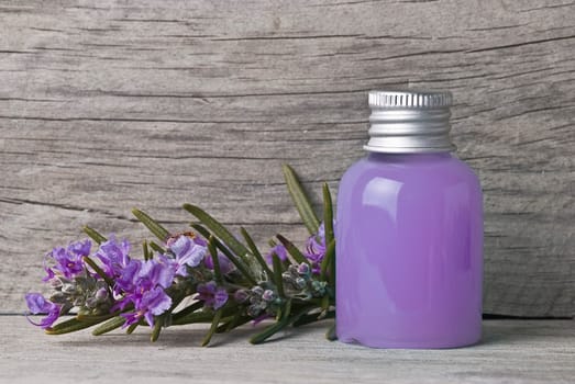 Rosemary branches with flowers and rosemary gel on an old wooden shelf.