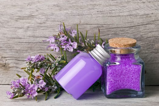 Rosemary branches with flowers and bath salts on an old wooden shelf.