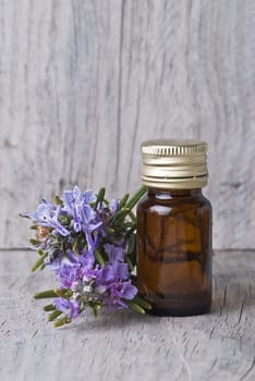 Rosemary branches and a bottle of rosemary essence on an old wooden shelf.