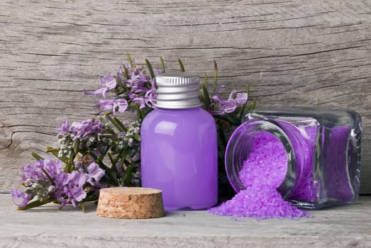 Rosemary branches with flowers and bath salts on an old wooden shelf.