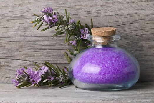 Rosemary branches with flowers and bath salts on an old wooden shelf.