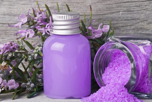 Rosemary branches with flowers and bath salts on an old wooden shelf.