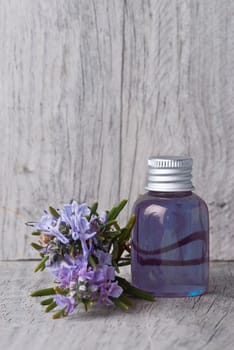 Rosemary branches with flowers and rosemary gel on an old wooden shelf.