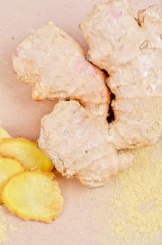 Fresh, dried and powdered ginger at brown background