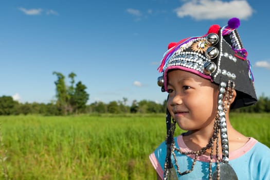Asian boy Akha,portrait with traditional headgear with rice field in background