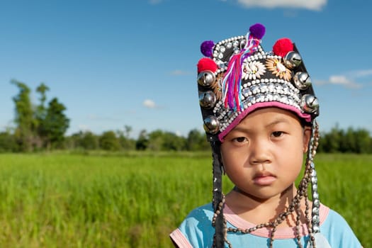 Asian boy Akha,portrait with traditional headgear with rice field in background