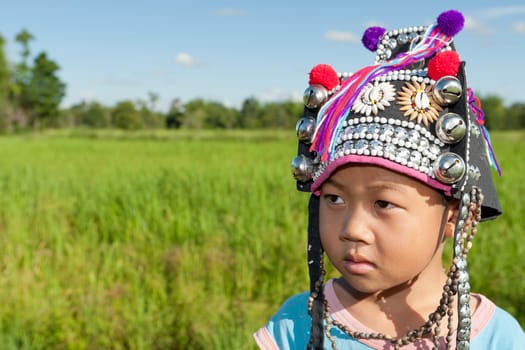 Asian boy Akha,portrait with traditional headgear with rice field in background