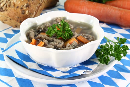 a bowl of liver spaetzle soup with carrots and parsley