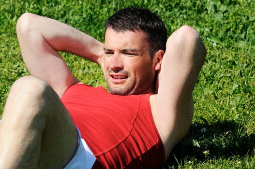 attractive man is doing situps in the fresh grass