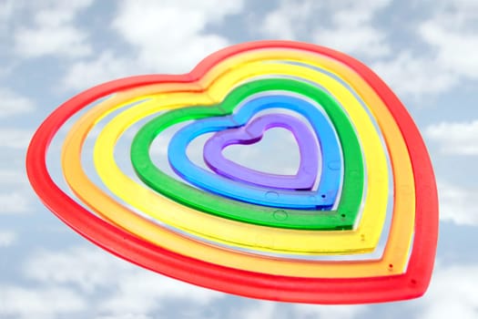 six heart shaped plastic pieces one inside the other on a cloudy background as if floating on air