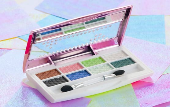 Eye shadow kit over colourful papaers background