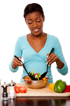 Beautiful health conscious young woman tossing healthy organic salad in kitchen, isolated.