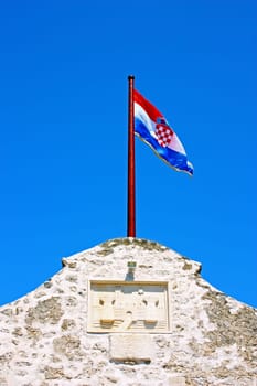 Croatian flag on the top of the wall at the entrance to the city Nin