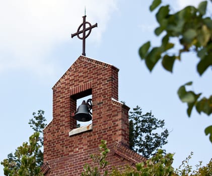 Church bell tower and bell with cross on the top of the construction
