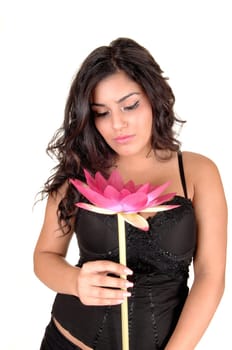 A lovely teenager with long black curly hair and a pink lily in her hand,  wearing a black corset and looking at her flower, for white background.