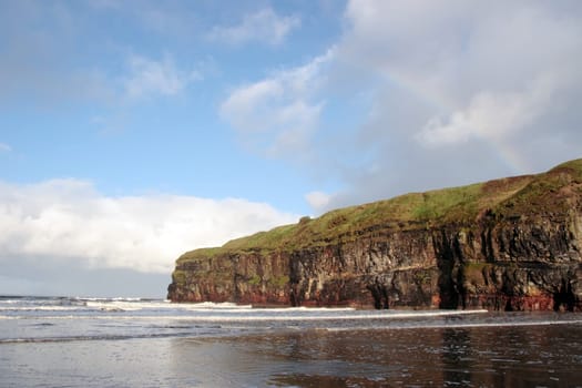 a view of the beach cliffs in ballybunion co kerry ireland with rainbow
