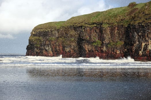 a view of the beach cliffs in ballybunion co kerry ireland with reflection during a snow storm