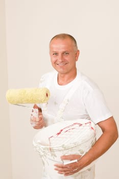 Home decorating mature man with paint roller, grid and bucket