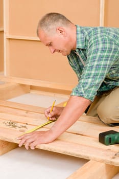 Mature handyman home improvement installing wooden floor in new house