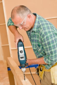 Handyman mature home improvement drilling wooden beam