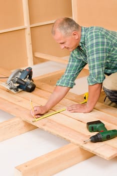 Mature handyman home improvement installing wooden floor in new house