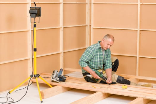 Mature handyman home improvement installing wooden floor in new house