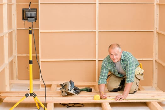 Mature handyman home improvement installing wooden floor in new house