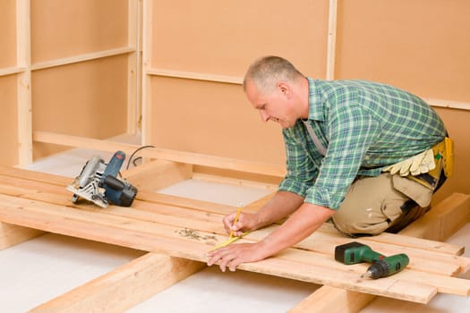 Mature handyman home improvement installing wooden floor in new house