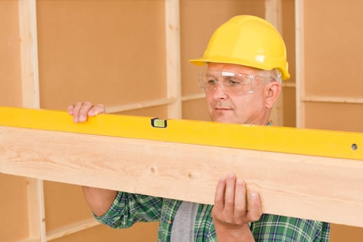 Handyman mature professional with spirit level working on home renovations