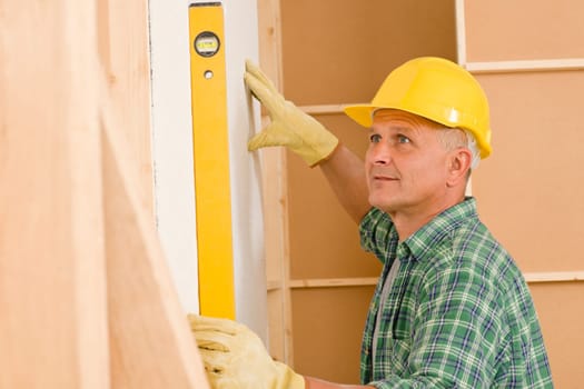 Mature professional handyman with spirit level working on home renovations