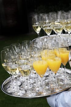 Champagne is served by waiters - many glasses of champagne and orange juice on the tray