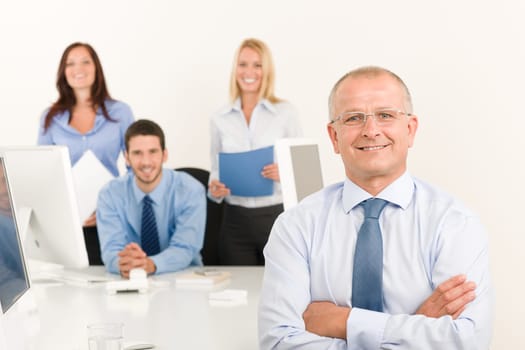 Business team happy mature businessman with attractive colleagues behind computer