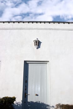 a blue grey front door on white wall with sky above