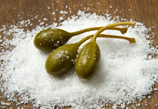 caperberries with salt close up on wood background