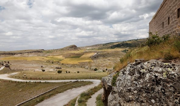 Cappadocia landscape of limestone wall windy dirt track  road public footpath lava rock farms plains hills cloudscape horizontal crop space and copy space
