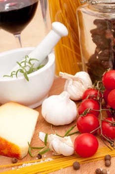 Italian Cuisine - spaghetti, tomatoes, dried tomatoes, pecorino cheese, garlic, rosemary in mortar, salt and glass of red wine
