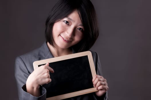 Happy woman in suit pointing to blackboard