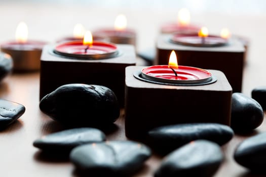 Close-up of black stones and red tea-light candles