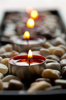 Close-up of red tea-light candles on pebbles