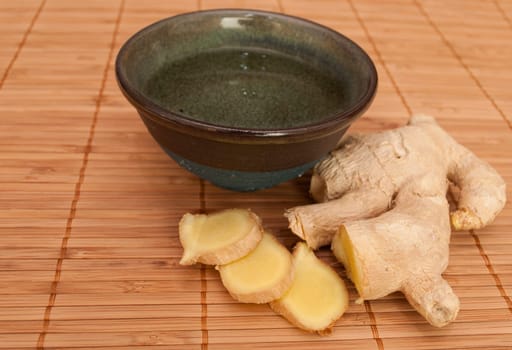 Cup of Tea and Pieces of Ginger on Reed Pad