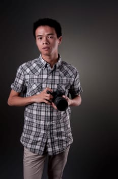 A young Asian man holding a SLR camera