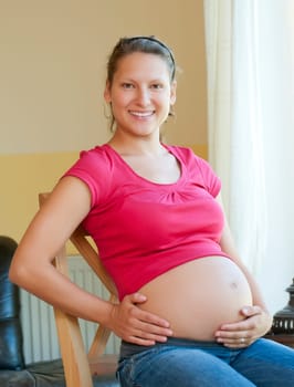 Pregnant young woman sitting on a chair