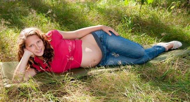 Pregnant young woman lying on a meadow