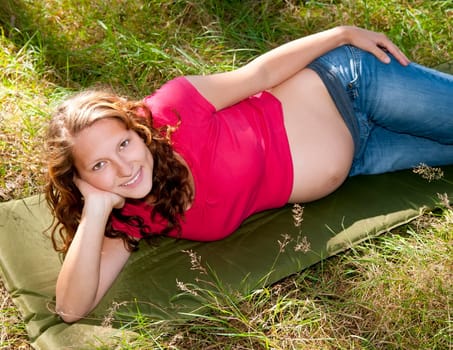 Pregnant young woman lying on a meadow