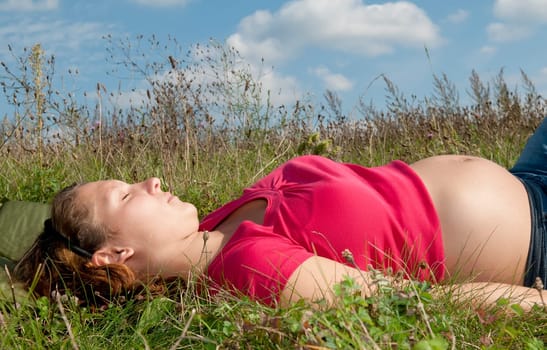 Pregnant young woman relaxing in a meadow