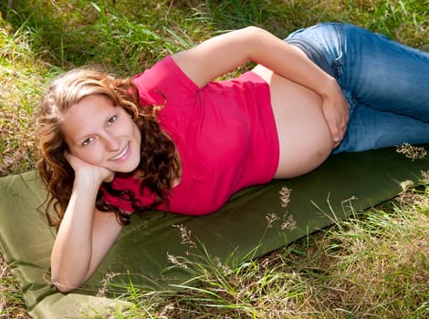 Pregnant young woman lying on a meadow
