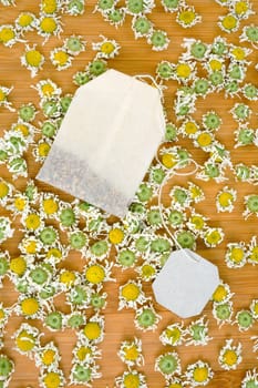 Bag of chamomile tea with dry chamomilla flowers over wooden background