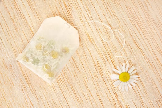 Bag of chamomile tea over wooden background - concept